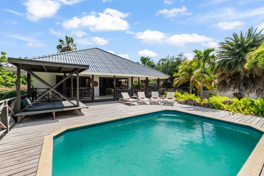 The pool with the wooden deck and the sunbeds
