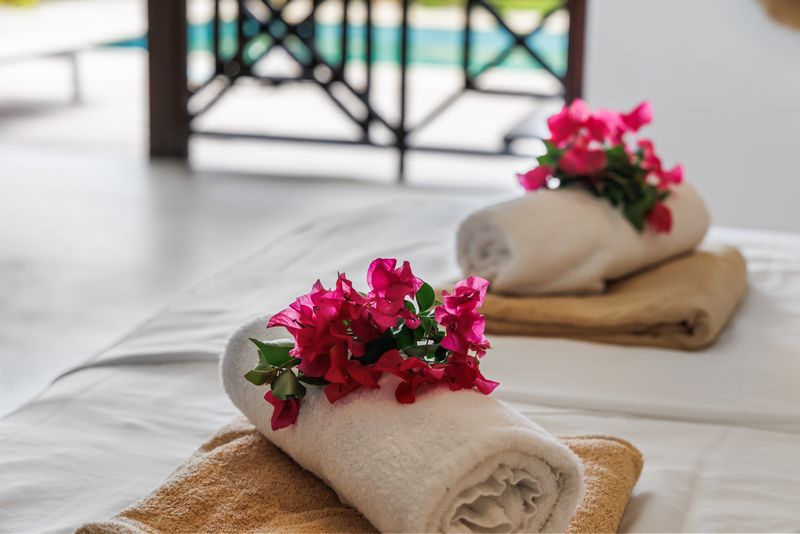 Rolled-up towels with bougainvillea on the bed